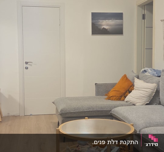 סלון עם ספה, שולחן עגול ודלת לבנה